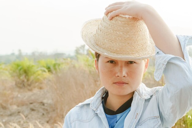 写真 空の向こうのフィールドで帽子をかぶった若い女性の肖像画