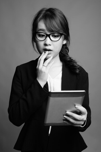 Фото Портрет молодой женщины с очками, стоящей на сером фоне