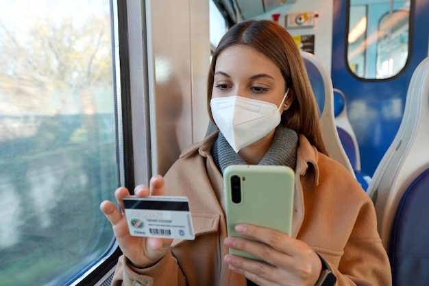 온라인 쇼핑을 위해 스마트폰으로 신용카드로 기차를 타고 여행하는 보호용 안면 마스크를 쓴 젊은 여성의 초상화