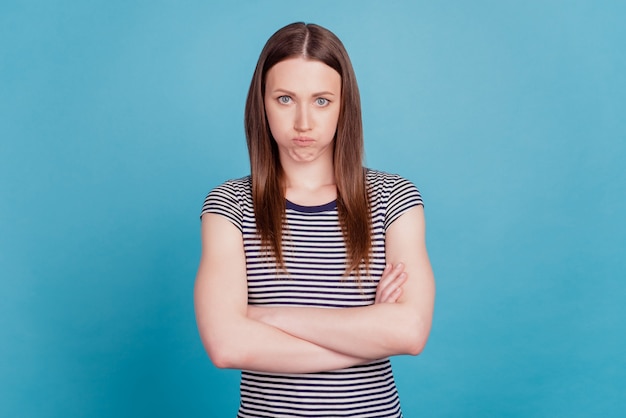 Portrait of offended grumpy upset girl crossed hands on blue background