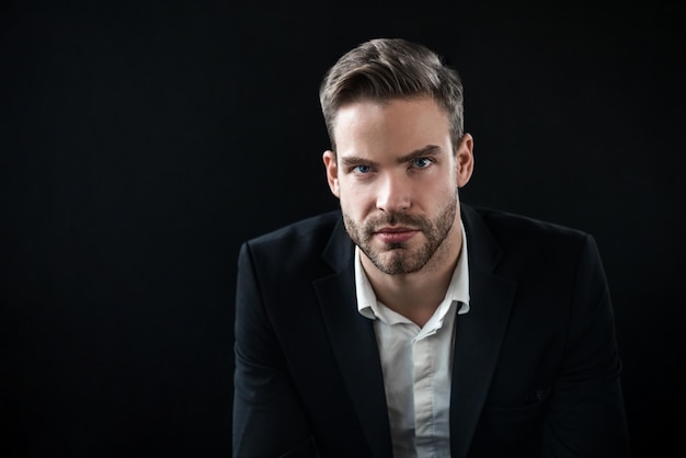 Portrait of office worker in black suit sitting on chair and looking on camera