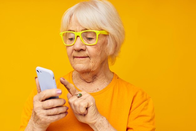 Portrait of an old friendly woman in casual tshirt communication by phone isolated background