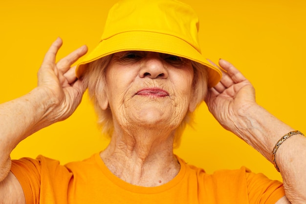 Portrait of an old friendly woman in casual tshirt yellow panama cropped view