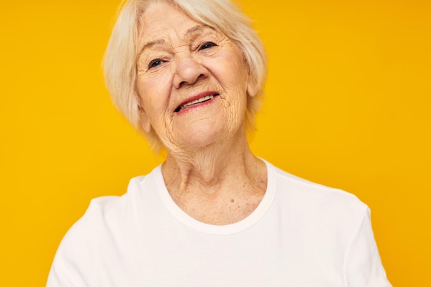 Portrait of an old friendly woman happy lifestyle joy yellow background