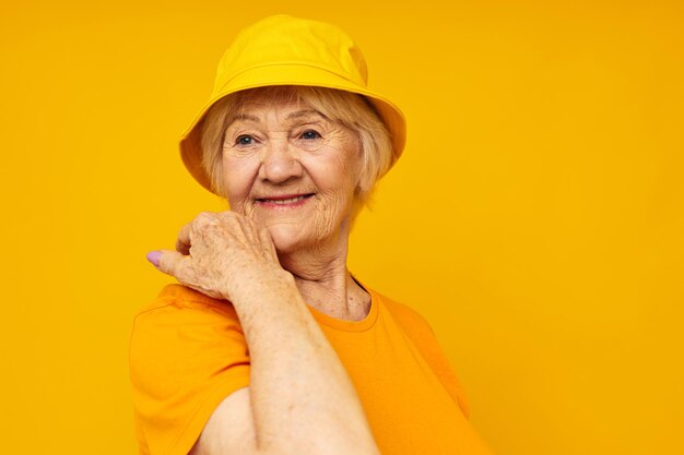 黄色の頭飾り黄色の背景で古いフレンドリーな女性の幸せなライフスタイルの肖像画