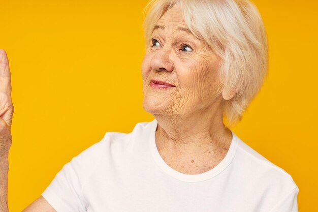 Portrait of an old friendly woman in white tshirt posing fun isolated background