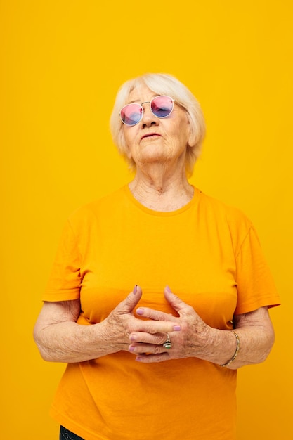 Portrait of an old friendly woman in a yellow tshirt posing isolated background