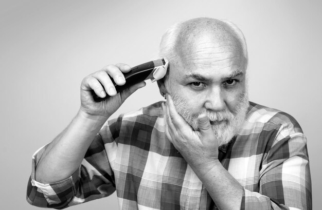 Portrait of old man being trimmed with hair clipper in barbershop haircut with an electric razor Man hair treatment