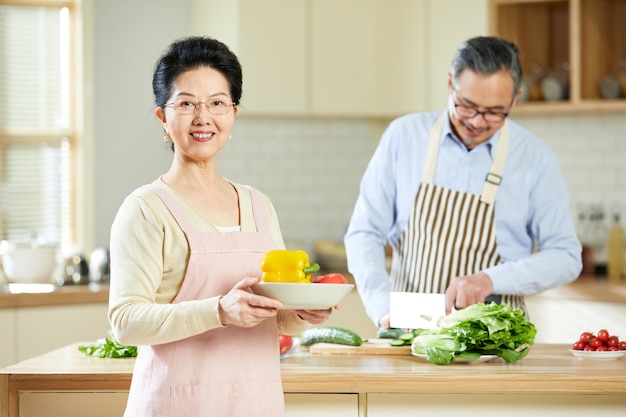 Portrait an old married couple looks cheerful in the kitchen room