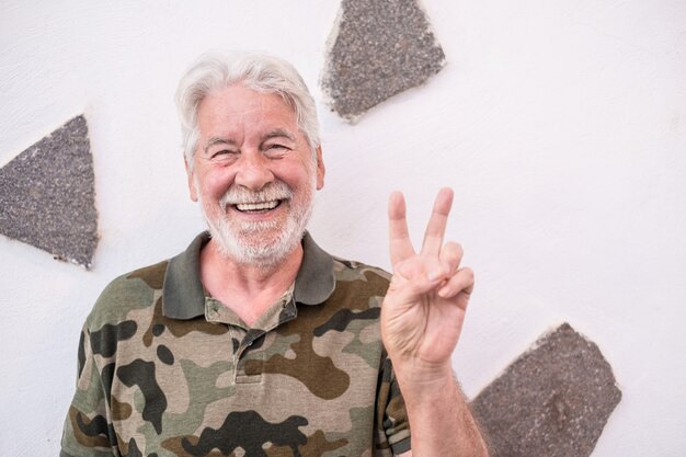 Portrait of old senior optimistic man smiling doing positive sign with hand. White haired face expression, white background