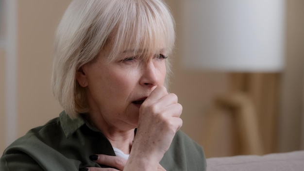 Portrait old woman coughing at home Close up unwell Caucasian aging mature lady coughs having pain