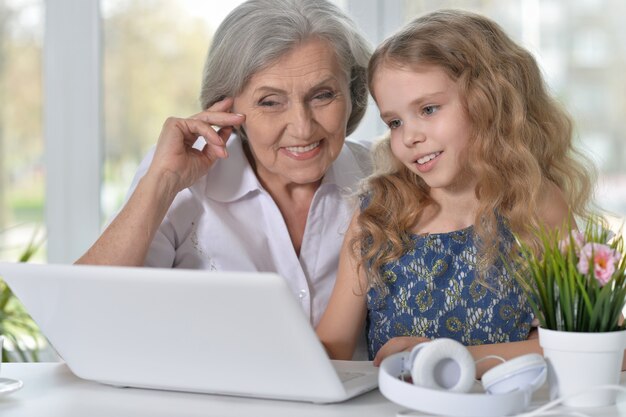 Portrait of an old woman and a little girl using laptop