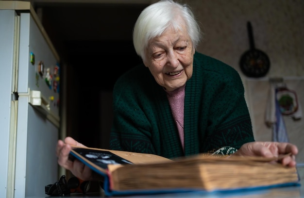 portrait of old woman looking album at home