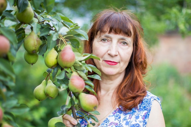 Ritratto di una donna anziana con frutti di peramistress in giardino