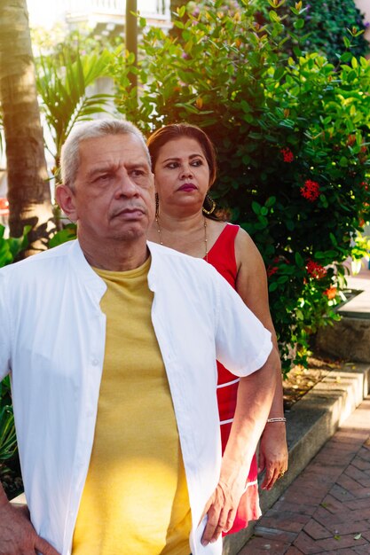 Portrait of an older couple outdoors looking out of the corner of their eyes.