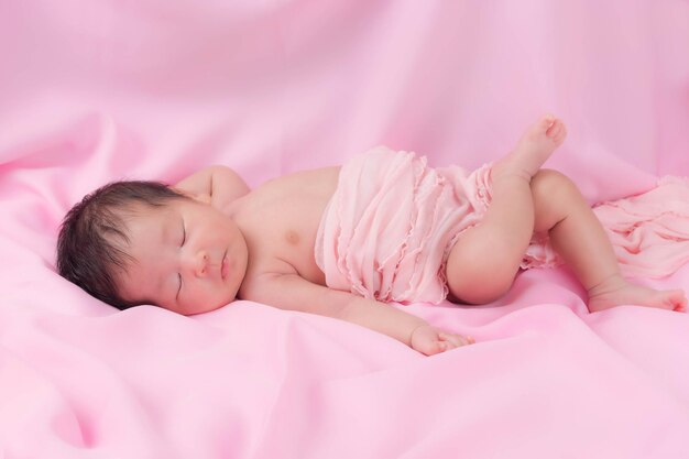 Portrait of a one month old sleeping, newborn baby girl on a pink blanket. Concept portrait studio fashion newborn.