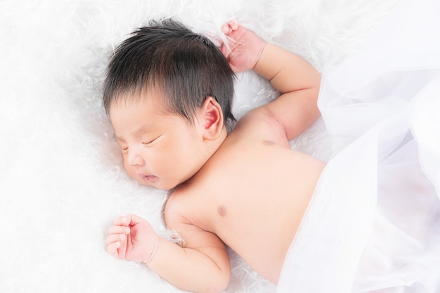 Portrait of a one month old sleeping, newborn baby girl on a white blanket. Concept portrait studio fashion newborn.