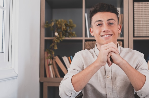 Portrait of one young and happy cheerful man smiling looking at the camera having fun. Headshot of male person working at home in the office.