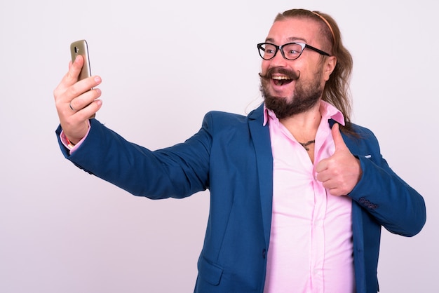 Portrait of overweight bearded businessman with mustache and long hair against white wall