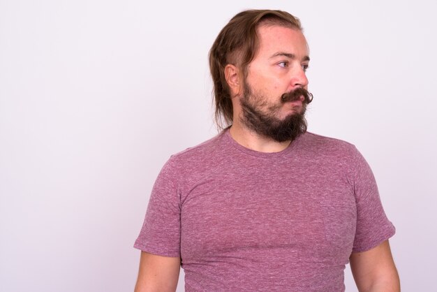 Portrait of overweight bearded man with mustache and long hair against white wall