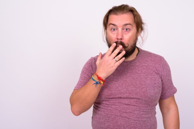 Portrait of overweight bearded man with mustache and long hair against white wall