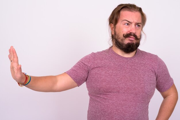 Portrait of overweight bearded man with mustache and long hair against white wall