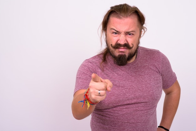 Portrait of overweight bearded man with mustache and long hair against white wall