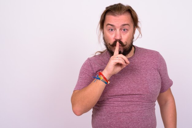 Portrait of overweight bearded man with mustache and long hair against white wall