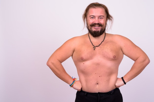 Portrait of overweight bearded man with mustache and long hair shirtless against white wall