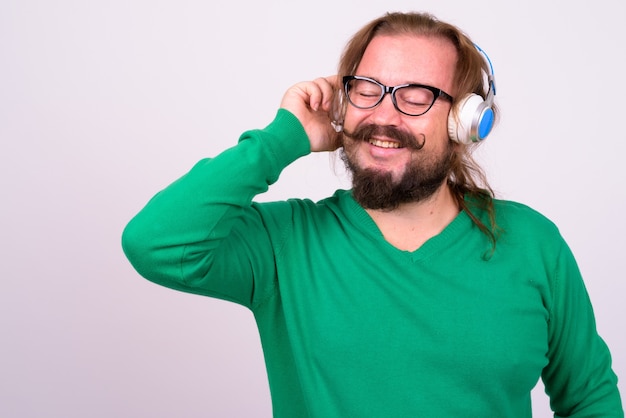 Portrait of overweight bearded man with mustache and long hair wearing green sweater against white wall