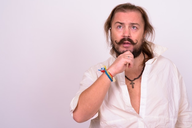 Portrait of overweight bearded man with mustache and long hair wearing white shirt against white wall