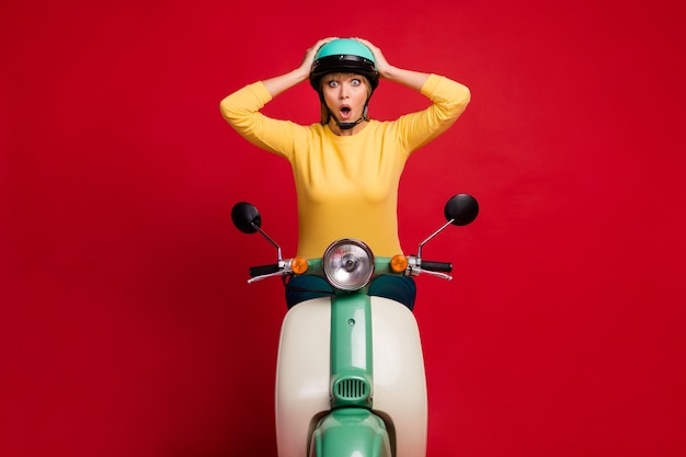 Portrait of overwhelmed girl sitting on moped shocked face