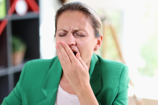 Portrait of overworked tired business woman yawning and covering face with hand frustrated and