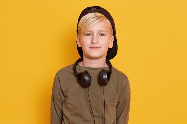 Portrait of pappy little boy posing isolated over yellow studio