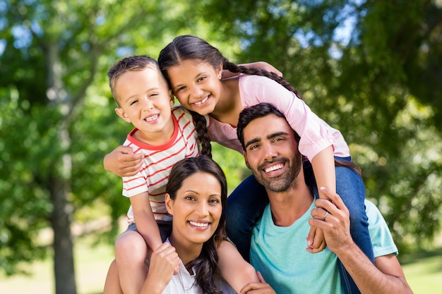 Portrait of parents carrying their children on shoulder in park