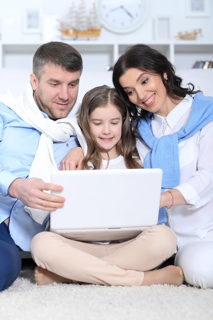 Portrait of parents and daughter using laptop in room