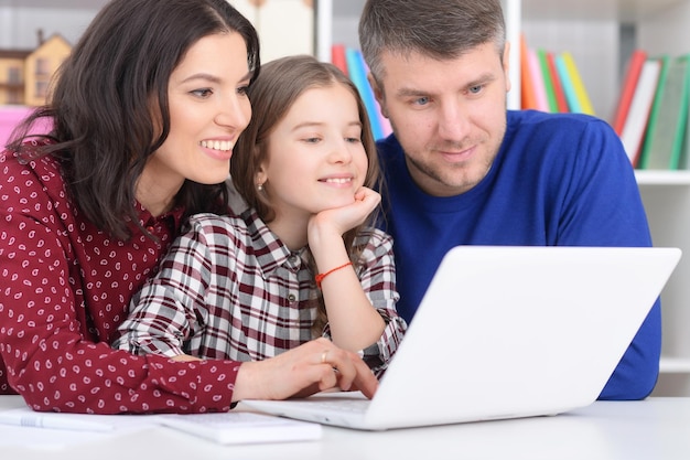 Ritratto di genitori e figlia che utilizzano laptop in camera