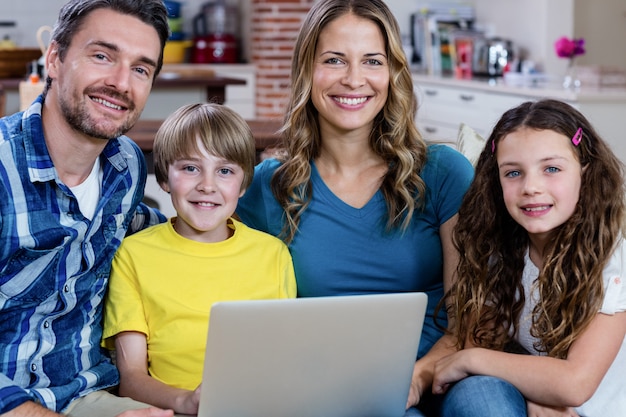 Portrait of parents and kids sitting on sofa and using a laptop