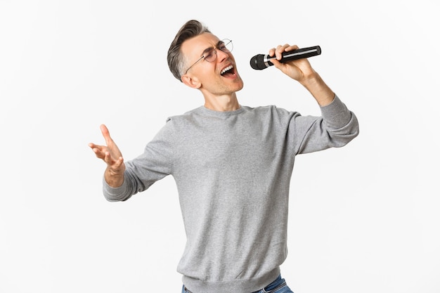 Portrait of passionate middle aged man singing serenade in microphone