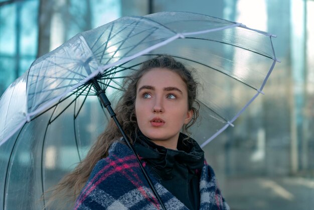 透明な傘を持つ肖像画ペンシブ若い女性 晴れた秋の日 魅力的な女の子が街を歩く