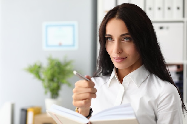 Portrait of a pensive beautiful businesswoman with pen and diary
