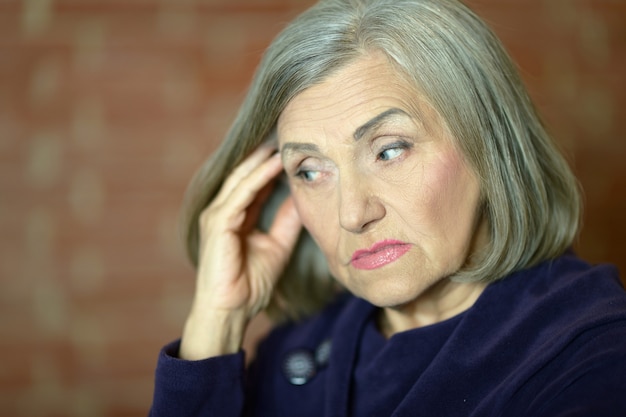 Portrait of a pensive elderly woman  in the room