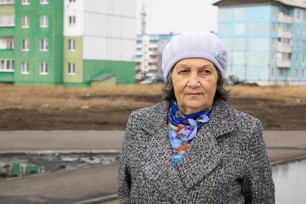 Portrait of a pensive elderly woman in warm clothes on the street in the city Cold weather