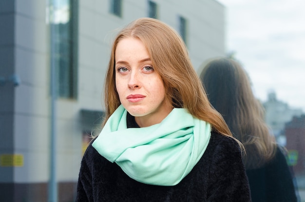 Portrait of pensive redhead woman with freckles and blue eyes outdoors