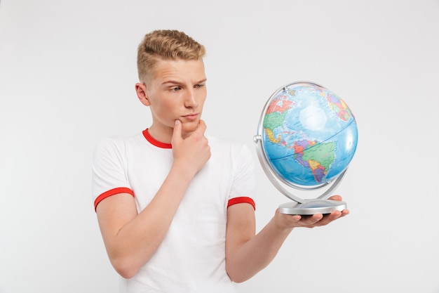 Ritratto di un adolescente pensieroso guardando un globo