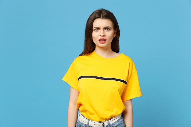 Portrait of perplexed bewildered concerned young woman in vivid casual clothes standing, looking camera isolated on bright blue background wall in studio. People lifestyle concept. Mock up copy space.