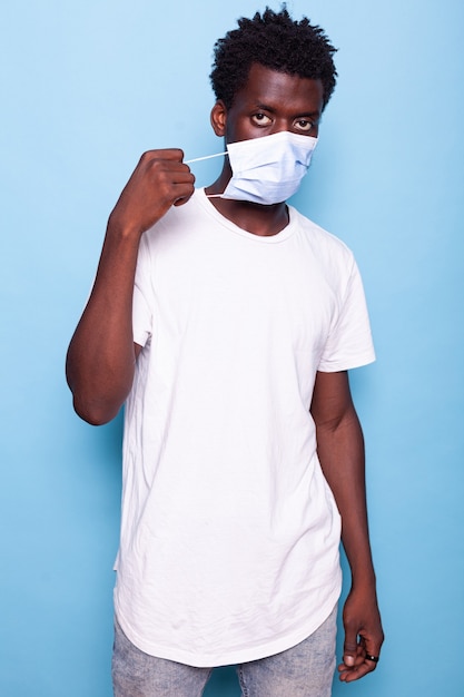 Portrait of person putting mask on face in studio