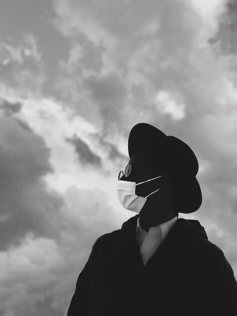 Photo portrait of person wearing corona face mask standing against sky