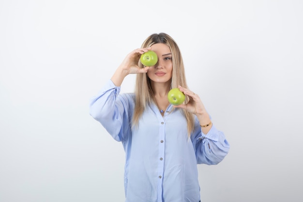 Portrait photo of a pretty attractive woman model standing and holding fresh apples .