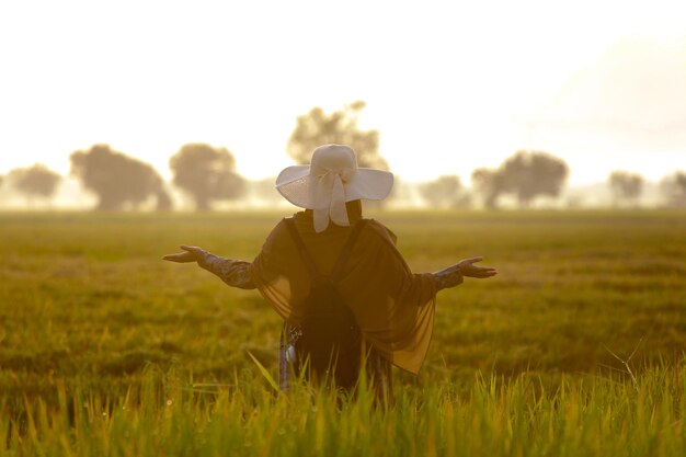 Photo portrait photo of woman walking among rural rice fields at sunrise